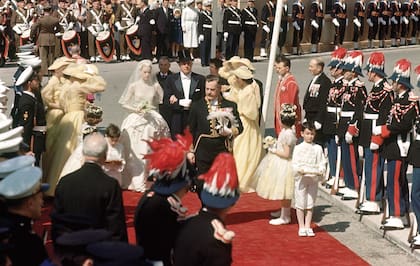 El 19 de abril de 1956, Grace Kelly llega a la catedral de San Nicolás del brazo de su padre John, para casarse con Raniero. Su vestido, que inspiró a novias como Kate Middleton y Sassa de Osma, era de encaje antiguo, tafetán, tul y seda, con perlas bordadas a mano, y fue creado por Helen Rose, diseñadora de MGM