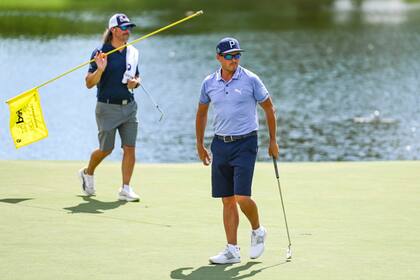 Rickie Fowler sale del green del noveno hoyo mientras el nuevo caddie Ben Schomin sostiene la bandera durante la práctica para el FedEx St. Jude, el primer playoffs de la FedExCup, en TPC Southwind