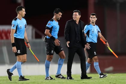 Gallardo y una sonrisa irónica al lado de los árbitros, después del partido.