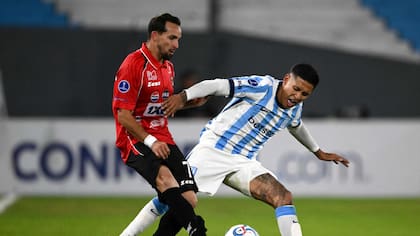 Robert Hernández (Caracas) y Matías Zaracho (Racing) luchan por la pelota