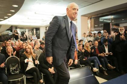 Roberto Lavagna avanza hacia el escenario frente a dirigentes de su partido político