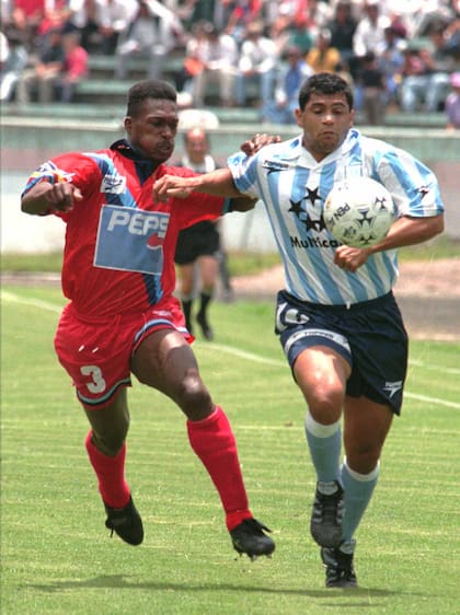 Roberto Saavedra, de Racing, intenta dejar atrás a Listron Valencia, de El Nacional, de Ecuador, en Quito (AP PHOTO)