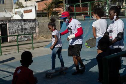 Robson Luiz, también conocido como MC Mingau, da clases de skateboarding a niños como parte del proyecto social CDD Skate Arte, en un parque público en la favela Cidade de Deus, en Río de Janeiro, Brasil, el jueves 5 de agosto de 2021. (AP Foto/Bruna Prado)