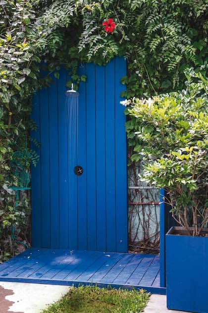 Rodeada de plantas, la ducha se encuentra en una estructura de madera pintada con esmalte sintético azul. Paisajismo: Eugenia Anaya.