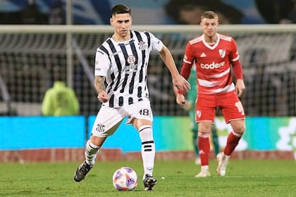 Rodrigo Villagra con la pelota al pie y la mirada adelante. Detrás suyo, Beltrán, en un duelo entre Talleres y River de 2023. El volante generó el pase más impactante del verano