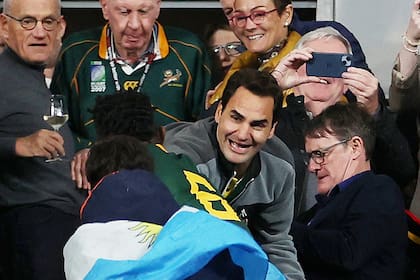 Roger Federer celebra con el capitán sudafricano Siya Kolisi en el Stade de France, detrás de un espectador envuelto en una bandera argentina; el ex tenista siguió la final del Mundial de Francia contra Nueva Zelanda como un hincha más de Springboks.
