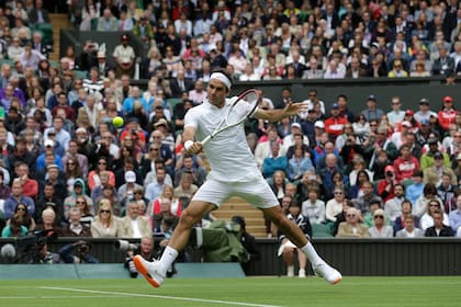 Roger Federer en acción durante un partido contra Victor Hanescu por la primera ronda del torneo de Wimbledon del 2013. Los organizadores le llamaron la atención al suizo por la suela anaranjada de sus zapatillas. Se supone que todo el atuendo tiene que ser blanco. Foto del 24 de junio del 2013. (AP Photo/Anja Niedringhaus, File)
