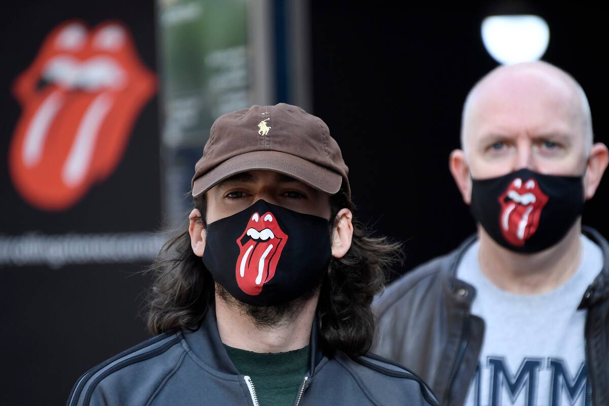 Rolling Stones fans wear face masks as they queue during the opening of Rolling Stones flagship store in London, Wednesday, Sept. 9, 2020. The shop will sell fashion and merchandise, as well as music, from the famous rock band.