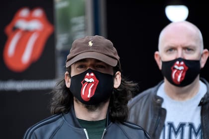 Fanáticos de los Rolling Stones con tapabocas de la banda esperan que abran las puertas de su primer negocio de ropa en Londres