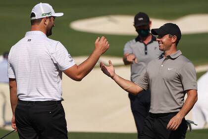Rory McIlroy (derecha), saludando al español Jon Rahm; el norirlandés va por el Major que le falta