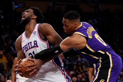 Russell Westbrook, de los Lakers de Los Ángeles, comete una falta sobre Joel Embiid, de los 76ers de Filadelfia, el miércoles 23 de marzo de 2022 (AP Foto/Ashley Landis)