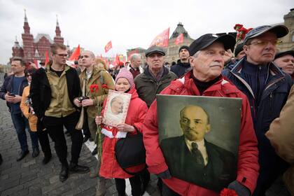 Russian Communist party members and supporters carry portraits of Vladimir Lenin as they walk towards the Mausoleum of the Soviet state founder and revolutionary leader Vladimir Ilyich Ulyanov aka Lenin to attend a flower-laying ceremony marking the 152th anniversary of his birth, on Red Square in Moscow, April 22, 2022. (Photo by Natalia KOLESNIKOVA / AFP)