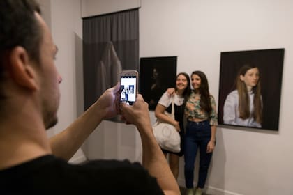 Dos chicas posan para la foto ante las fotos de Lihuel González, uno de los premiados en el rubro fotografía