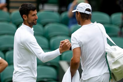 Saludo de leyendas: el serbio Novak Djokovic y el español Rafael Nadal, durante una sesión de entrenamiento en la cancha central de Wimbledon, antes del arranque del tercer grande del año.