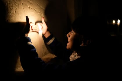 Samantha Alcívar juega con una vela en la panadería de sus padres durante un apagón eléctrico por racionamiento en Quito, Ecuador, el martes 15 de octubre de 2024. (AP Foto/Dolores Ochoa)