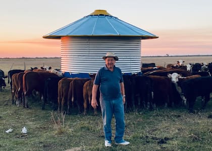 Santiago Castillo en el establecimiento San Pedrito, detrás un lote de terneros comiendo en un silo de autoconsumo