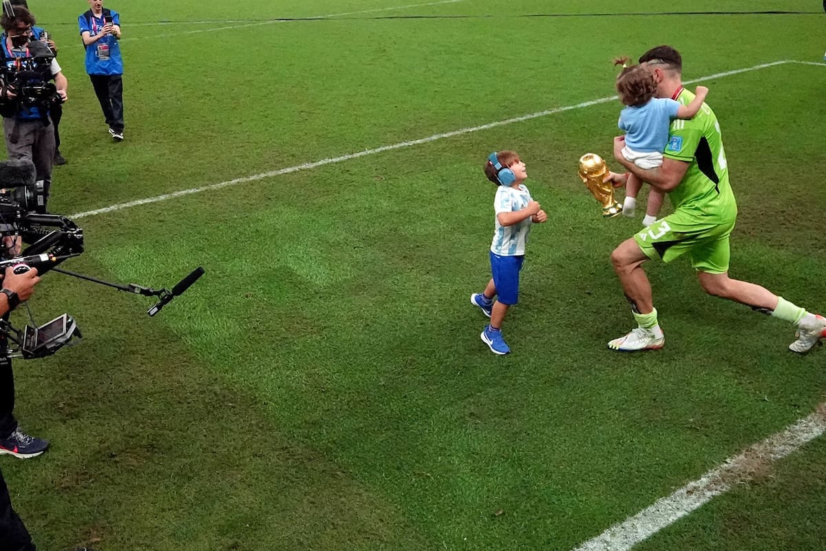 LUSAIL CITY, QATAR - DECEMBER 18: (EDITORS NOTE: In this photo taken from a remote camera from inside the goal) Argentina's Emiliano Martinez celebrates winning the World Cup with the trophy and his family after the FIFA World Cup Qatar 2022 Final match between Argentina and France at Lusail Stadium on December 18, 2022 in Lusail City, Qatar. (Photo by Carl Recine - Pool/Getty Images