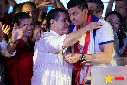 Santiago Peña, candidato presidencial del gobernante Partido Colorado, a la derecha, abraza al expresidente Horacio Cartes tras el cierre de votaciones que le dieron un amplia victoria en las elecciones generales, en Asunción, Paraguay, el domingo 30 de abril de 2023. (AP Foto/Jorge Sáenz)
