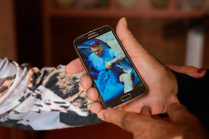 Santiago Sánchez muestra una foto de su hijo, que no tiene comunicación desde hace más de tres semanas. (AP Photo/Paul White)