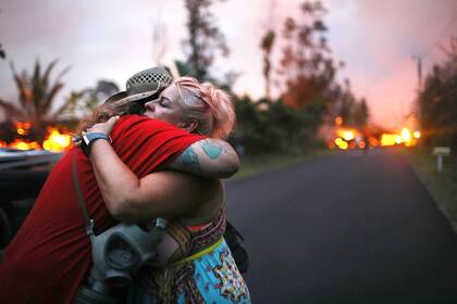 Dos mujeres se abrazan luego de una de ellas perdiera su casa bajo la lava del volcán