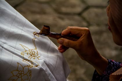 Se aplica la cera a la tela para hacer diseños que no se vean afectados por el tinte