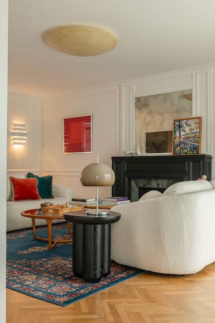Se mantuvieron el piso de parquet, las molduras y la chimenea del living, que se actualizó con pintura negra a poro abierto. Mesa de arrime 'Boterito' (Estudio Molé) con velador opalino.