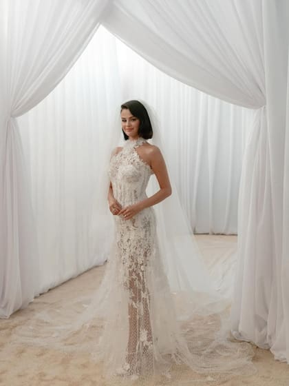 Selena Gomez vistió un vestido personalizado de Ralph Lauren, en satén blanco con escote halter, detalles florales bordados, espalda descubierta, cola larga, evocando un estilo clásico con toques románticos
