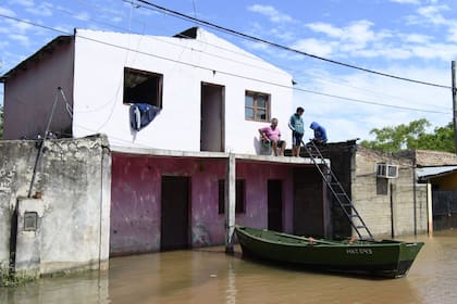 Sentado en una silla de plástico en la planta alta de su casa, tomando mate un hombre espera que pase la crecida