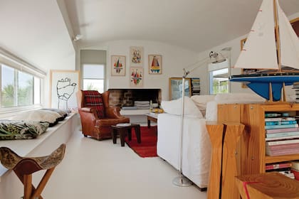 Separado del comedor por un desnivel de tres escalones, el sector del estar tiene una altura más baja que lo hace más acogedor. Sillón de cuero (Trading Post) y sofá en lino blanco (Dolores Álzaga) frente al hogar coronado por cuatro serigrafías compradas en José Ignacio.