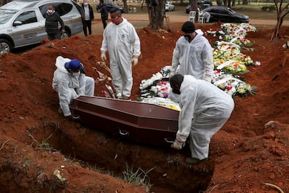 Sepultureros con trajes protectores se preparan para enterrar el ataúd que contiene el cuerpo de Elisa Moreira de Araujo, de 79 años, sospechoso de haber muerto por la enfermedad del coronavirus, en el cementerio de Vila Formosa, en Sao Paulo, Brasil.