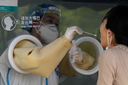 Un trabajador toma una muestra de hisopado en un centro de pruebas de COVID el martes 26 de abril de 2022 en Pekín