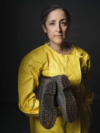Sheri Fink, reportera del equipo de investigación de The New York Times, aparece con su traje de protección y sosteniendo las botas que utilizó durante la cobertura del brote de ébola de 2014 en África Occidental