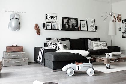 Si la dupla blanco/negro te parece demasiado, podés cortarla con algún mueble de madera. En este living se eligió una mesa ratona hecha con pallets y ruedas negras