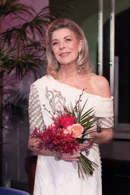 Siempre elegante, Carolina optó por un vestido blanco de inspiración nupcial, de escote asimétrico y con detalles florales en plata, de Chanel. Lo complementó con un espectacular broche: el Reed Stomacher de Chaumet, regalo de su amigo, Karl Lagerfeld.