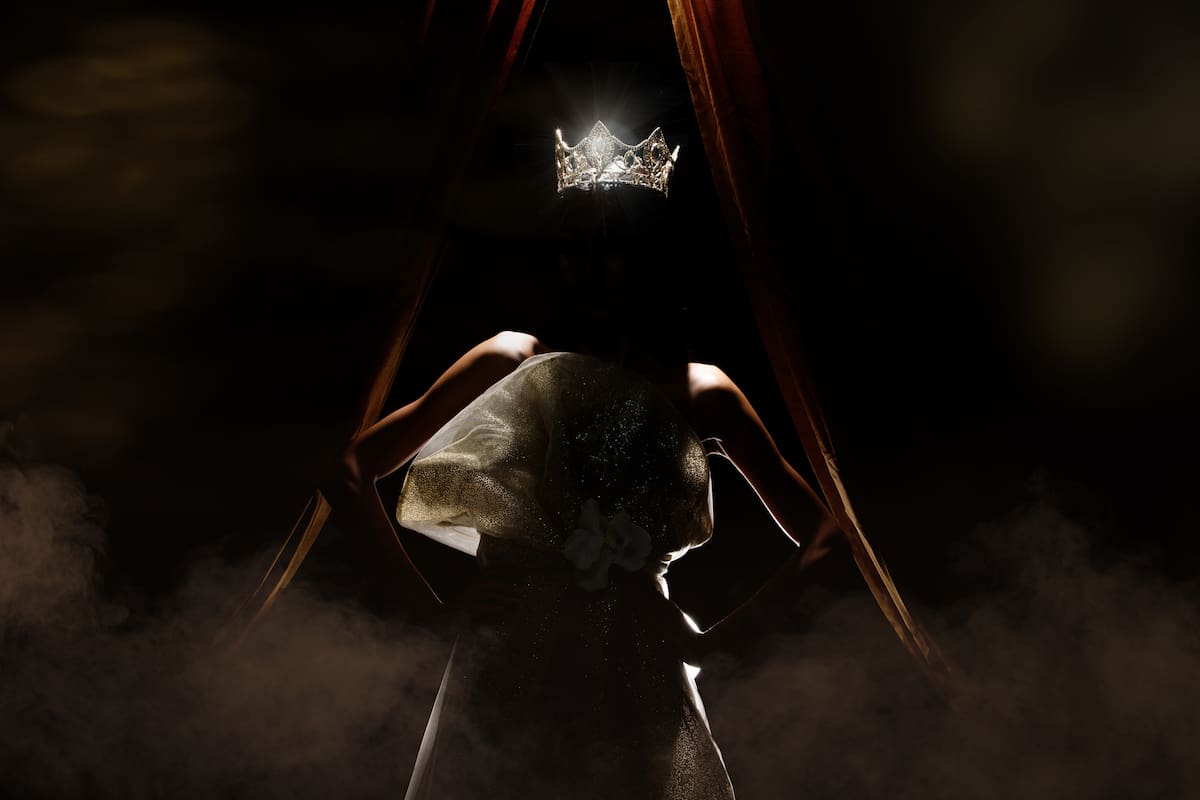 Silhouette of Miss Beauty Pageant Contest Woman with sparkle Diamond Crown with tanned skin beautiful makeup evening gown on stage with lighting curtain and dark background