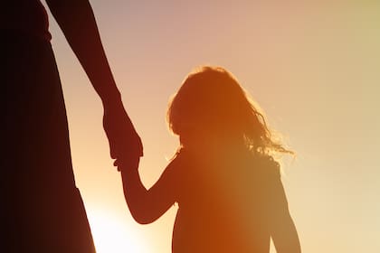 silhouette of mother and daughter holding hands at sunset