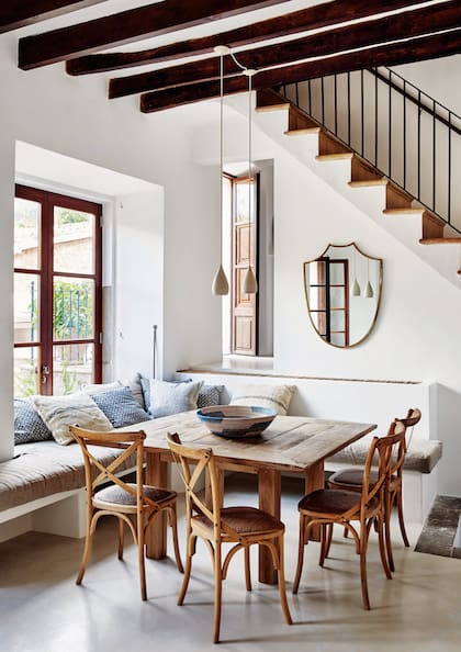 Sillas ‘Madeleine’ de madera y caña (Restoration Hardware) y bancos de obra rodeando la mesa hecha por el artesano carpintero Pedro Casanovas.