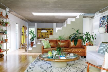 Sillón ‘Brem’ de cuero (Macacha Taller) con almohadones cuadrillé estampados a mano (Mercedes Segura). Mesa ratona con borde de cuero (Deco Todo Vuelve). Alfombra (Kalpakian).