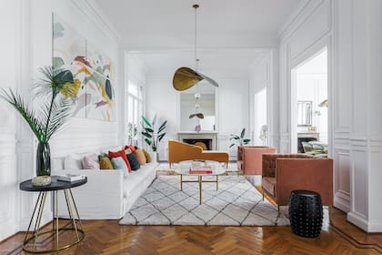 Sillón con funda de tussor (Bakana Interiorismo). Almohadones (Mercedes Segura). Tríptico ‘Evolución’. Mesa de centro con tapa de Neolith ‘Calacatta Gold’ (Casa Lulú Design). Butacas con respaldo capitoné (Bakana Interiorismo).