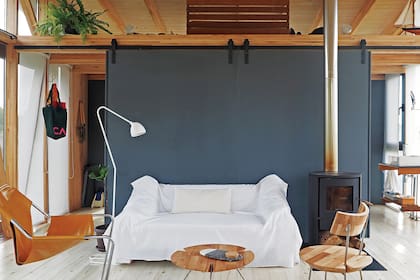 Sillón ‘Paulistano’, de Paulo Mendes da Rocha, y lámpara de pie ‘Uncuerno’ (A3). Silla en hierro y eucalipto y mesita redonda ‘Ramas’ (todo de Somos Nu). El piso y el cielo raso son de pino tratado.