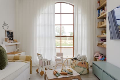Sillón tapizado en tussor y cortinas de gasa de pared a pared. Mesa baja heredada. Cocinita (Wonderplay).