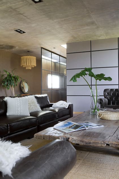 Sillones de cuero (By Ignacio Ortiz) con almohadones (Claudia Adorno y Cozy Home Deco). Manta artesanal (Elementos Argentinos). Mesa de centro con pie de hierro y tablas recuperadas (Hugo Tonti).