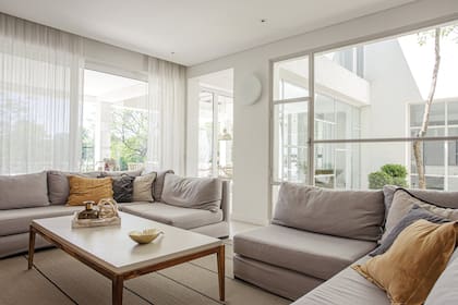 Sillones diseñados a medida y tapizados en lino con doble funda, almohadones, mesa de centro ‘Oslo’ laqueada con tapa entelada en gasa y cortinas de lino (todo de Muliere-Padilla)