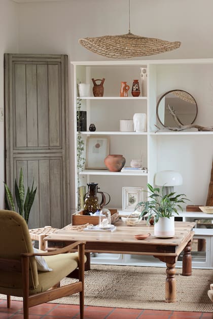 Sillones nórdicos modernistas se combinan con muebles de campo y alfombras de raffia en el living.