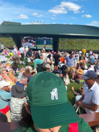 Silvina Funes, presidenta del club de fans oficial del serbio, luce orgullosa la cabra con la vista de los fans en un lugar emblemático de Wimbledon, "The Hill"