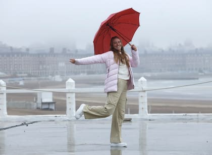Simpática postal marplatense: la tenista Solana Sierra, divirtiéndose bajo la lluvia, en la terraza del Torreón del Monje, con el Casino de fondo
