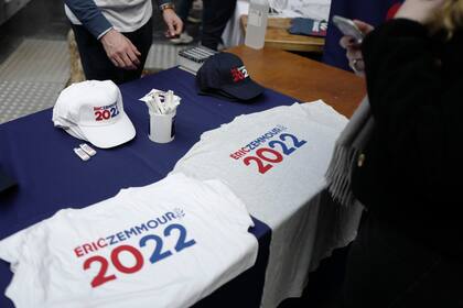 Simpatizantes del candidato de extrema derecha a la presidencia Eric Zemmour venden camisetas y gorras previo al primer mitin de campaña del candidato, el domingo 5 de 2021, en Villepinte, al norte de París. (AP Foto/Rafael Yaghobzadeh)