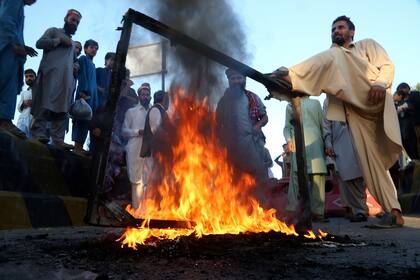 Simpatizantes del partido del exprimer ministro Imran Khan queman neumáticos y otros materiales mientras bloquean un camino en Peshawar, Pakistán, en protesta contra una decisión de la comisión electoral, el viernes 21 de octubre de 2022. (AP Foto/Muhammad Sajjad)