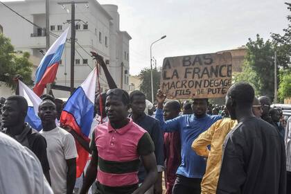 Simpatizantes ondean banderas rusas y una pancarta con un lema contra Francia mientras se manifiestan en apoyo de la junta de Níger en Niamey el 30 de julio de 2023.