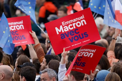 Simpatizantes sostienen pancartas con la leyenda "Emmanuel Macron contigo" antes de la llegada del presidente francés y candidato del partido La Republique en Marche (LREM) a la reelección, Emmanuel Macron, en el Campo de Marte, en París, el 24 de abril de 2022.